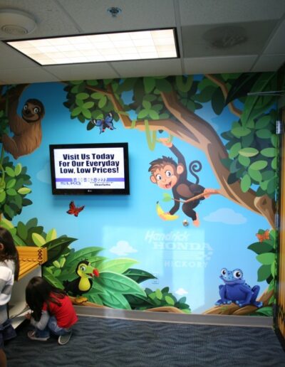 Colorful playroom with jungle-themed mural, kids playing, and a TV displaying a message.