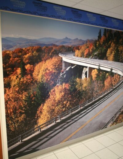 Mural of a winding road through vibrant autumn foliage against a mountainous backdrop.