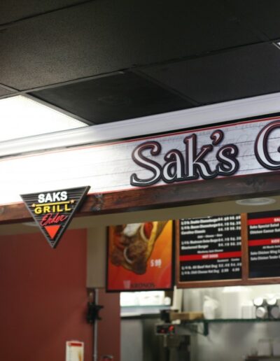Sak's Grill sign displayed above a menu board in a casual dining setting.