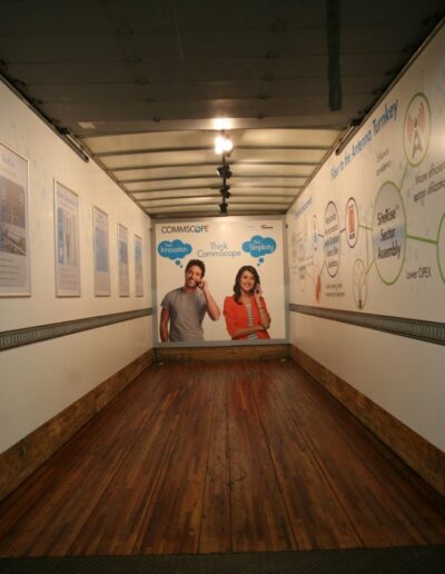 Empty truck interior with wooden flooring, featuring wall posters and two large printed figures.