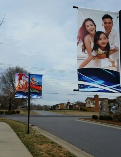 Banners featuring families and colorful designs along a sidewalk in a suburban area.