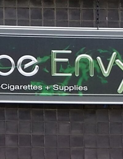 Sign for Vape Envy, featuring green lettering and stating "e-Cigarettes + Supplies" underneath.