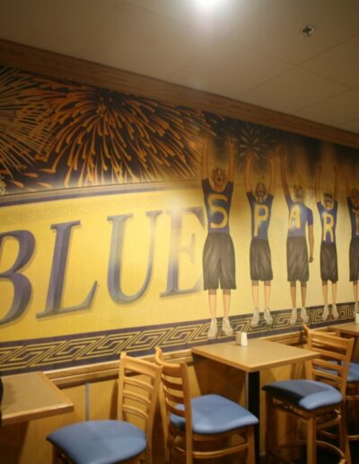 A mural on a wall depicts cheerleaders and the word "BLUE" in bold letters under a Spartan helmet.