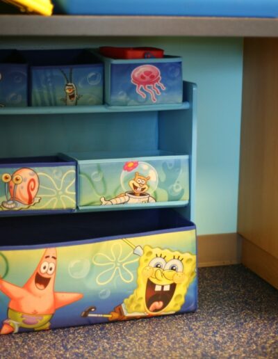 Colorful storage bins featuring SpongeBob SquarePants characters in a playroom setting.